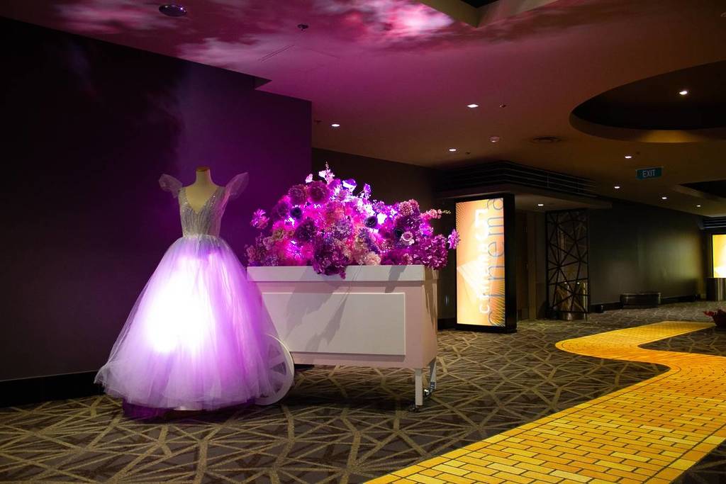 Glinda's dress on display next to a yellow brick road at Village Cinemas