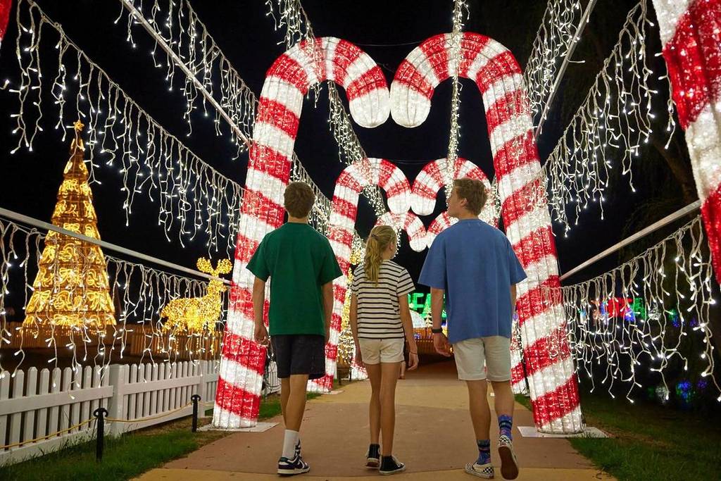 children walking on a path framed by glittering candy cane installations at the Christmas Festival of Lights at Adventure Park