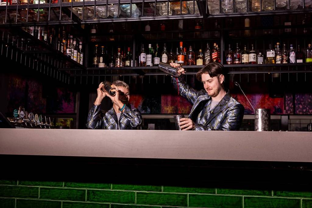 bartenders making a drink at Rooftop at QT, wearing shiny blazers for New Year's Eve