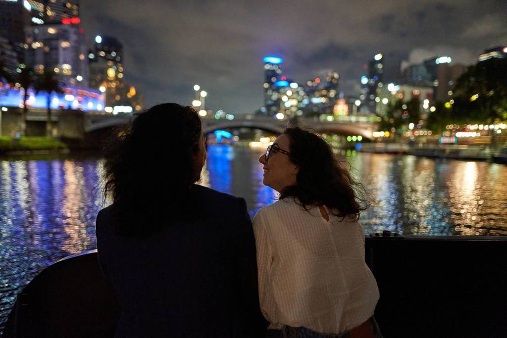 two women looking at the twinkling skyline while on a boat with Melbourne River Cruises