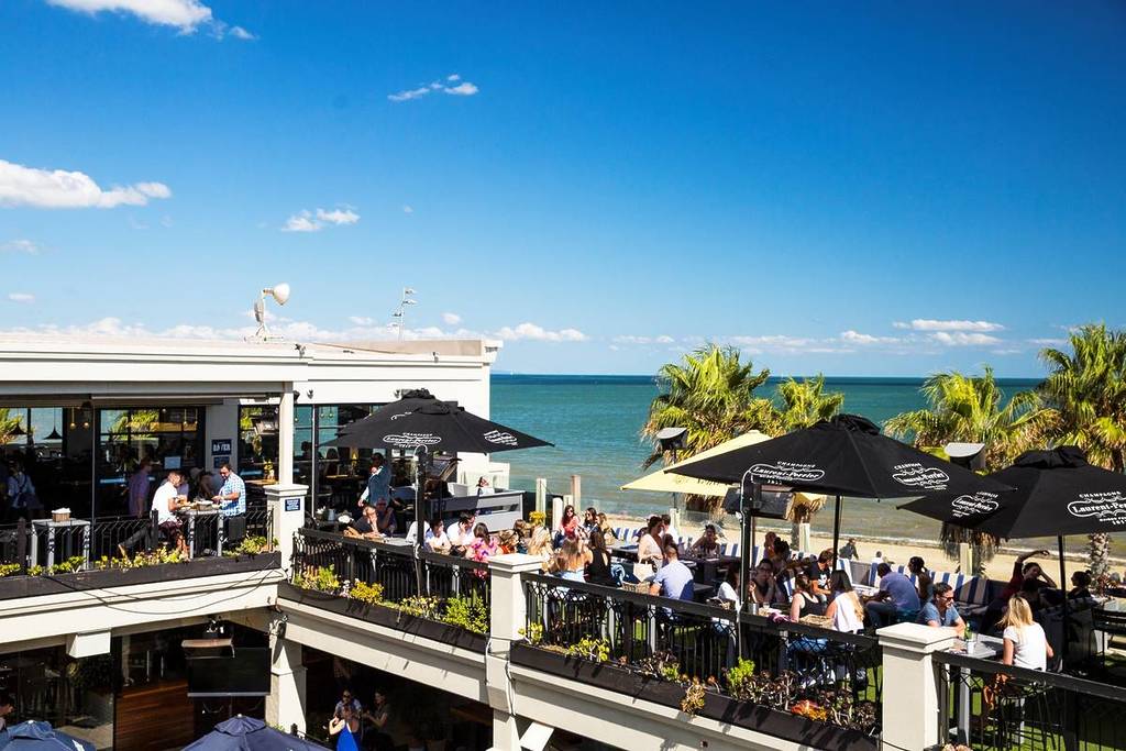 people dining on the upper level of Republica with St Kilda beach in the background