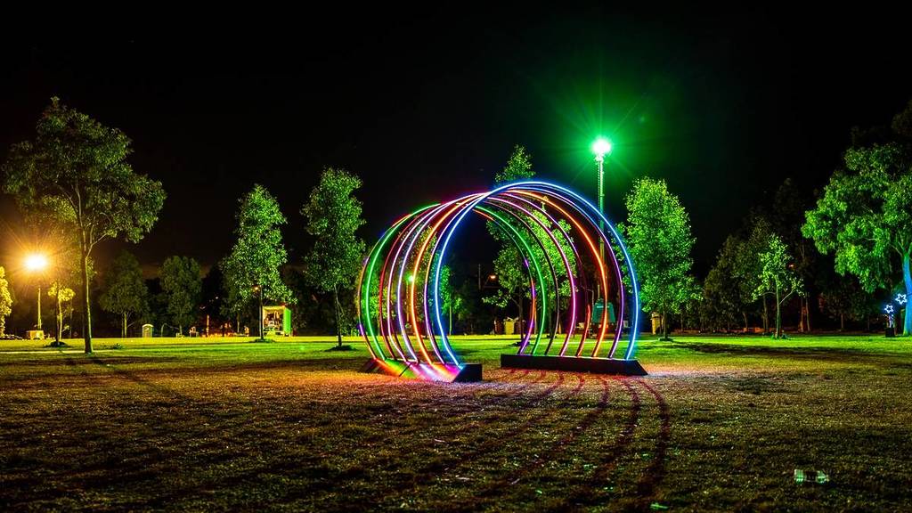 neon installation that looks like a colourful tunnel in a park