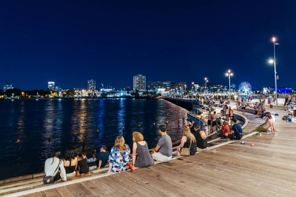 people hanging out and sitting down on St Kilda Pier at night