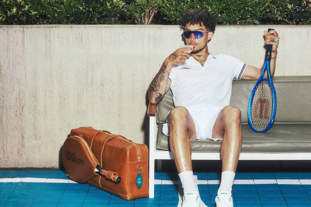 man in tennis clothes sipping a cocktail on a bench