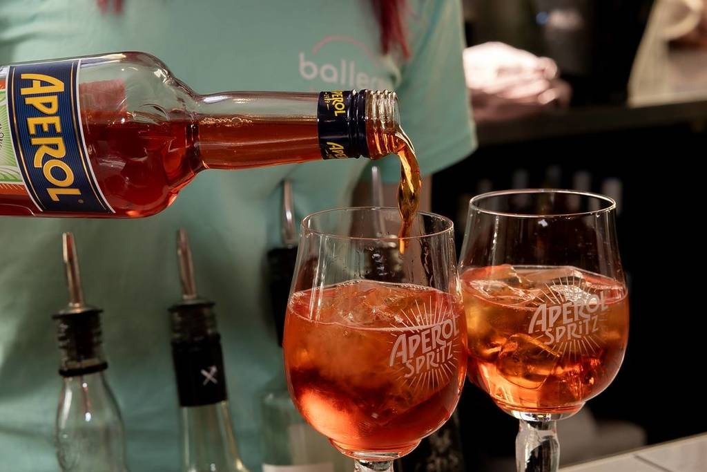 woman pouring out two Aperol Spritz cocktails at Ballers Clubhouse