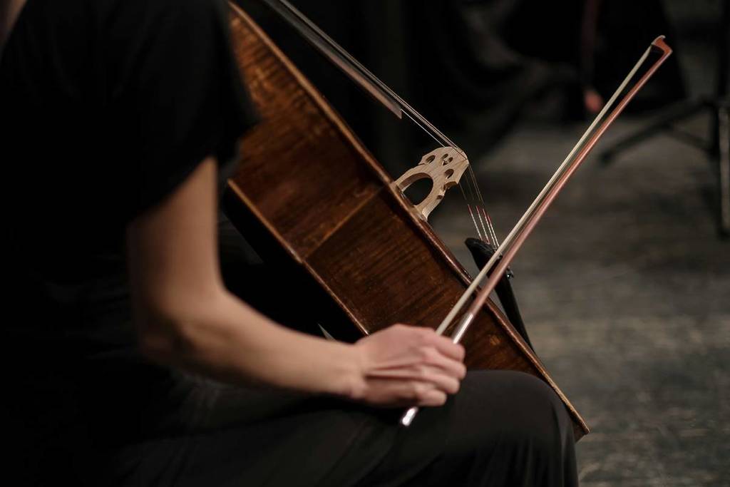 A close up of a cellist performing at a classical concert