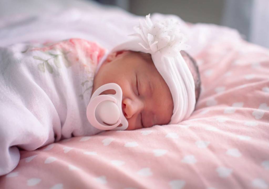 baby girl wearing a pacifier and sleeping