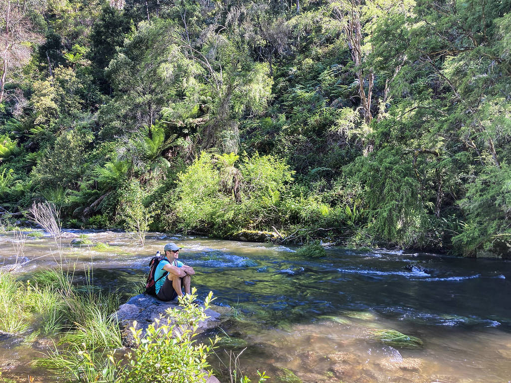 hiker sitting on a rock by the river on the Mount Beauty Gorge Walk
