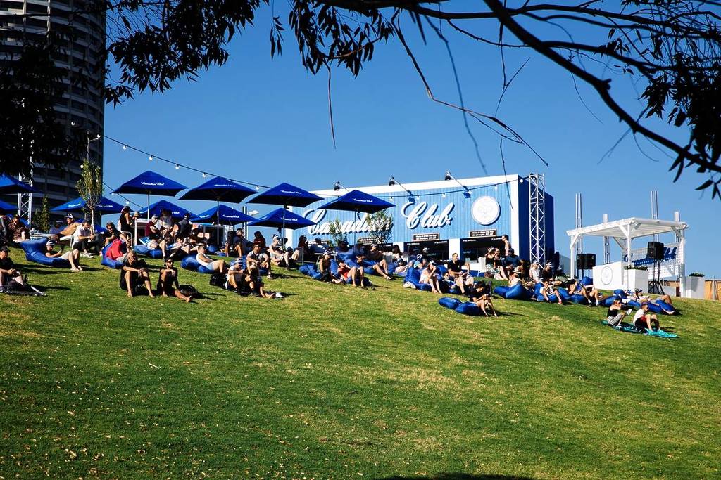people chilling on AO Hilltop with signage for Canadian Club Racquet Club