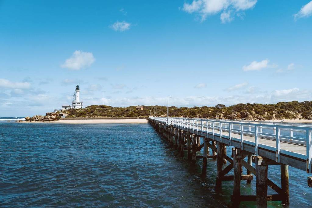 view from the pier in Point Lonsdale of the beach and the lighthouse in the distance