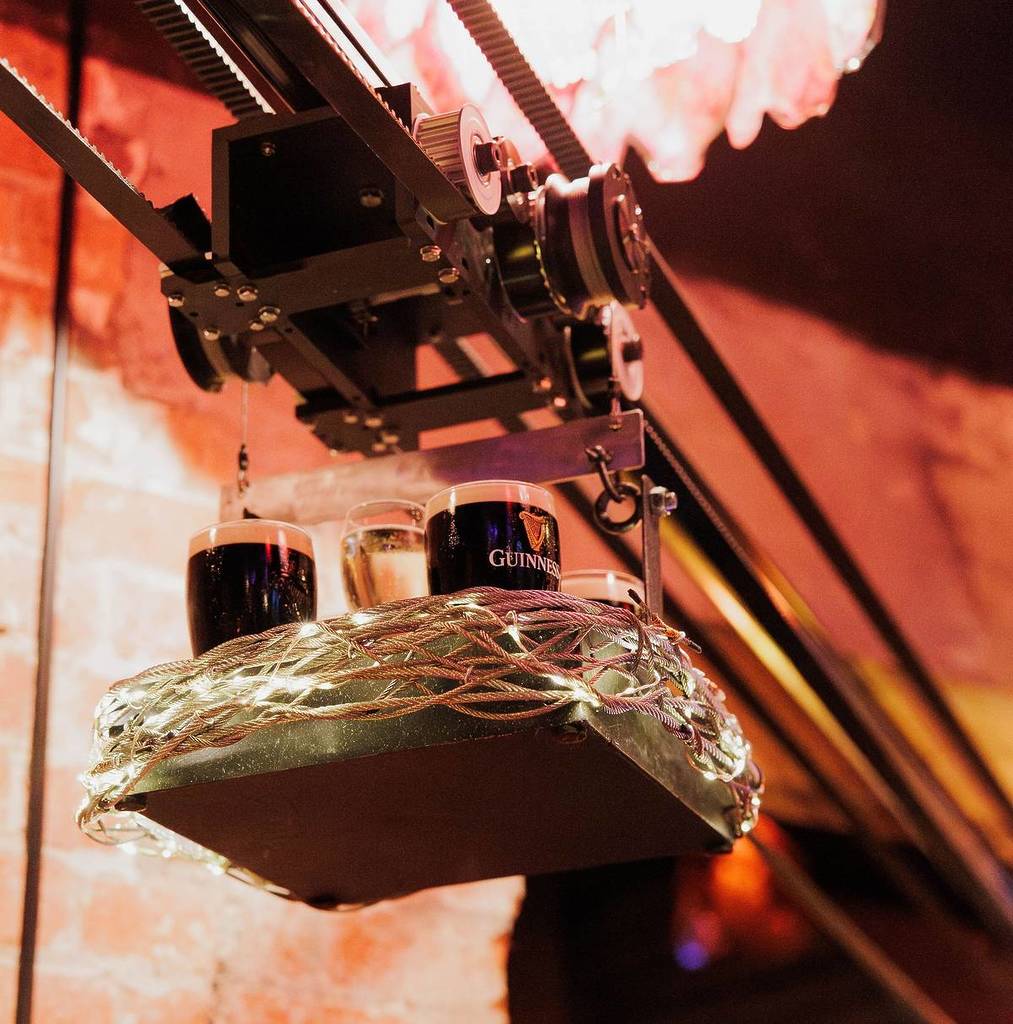 drinks like Guinness in a basket being delivered through the air on a zipline system