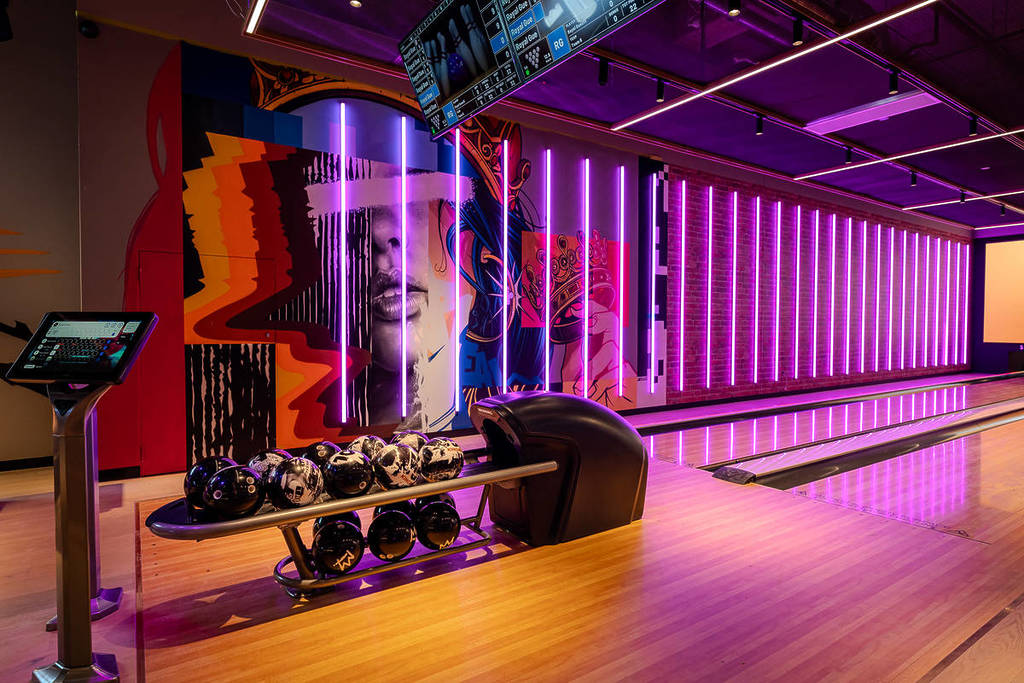 bowling balls and lanes, with a gritty street art portrait on the wall and strips of purple lights at Kingpin Melbourne Collins Arcade