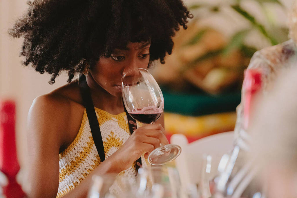 A close-up of a woman breathing in the smell of red wine from a glass at Tastes of Rutherglen.