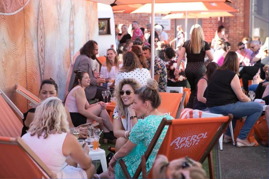 people sitting outdoors, drinking and chatting amongst themselves at the prosecco festival