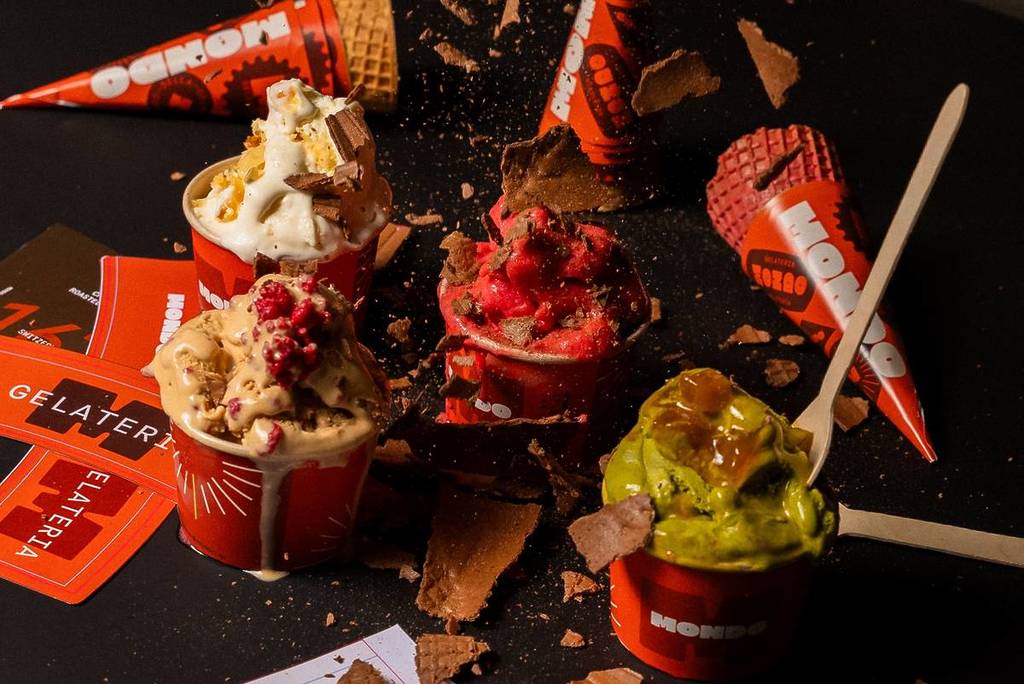 different types of gelato in cups and cones on a table