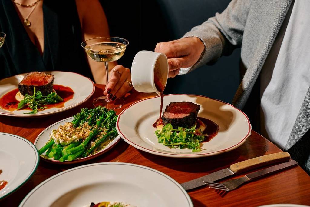 man pouring sauce over beef tenderloin at Lollo