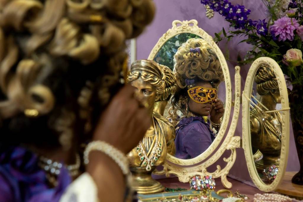 queen looking at herself in the mirror holding up a mask