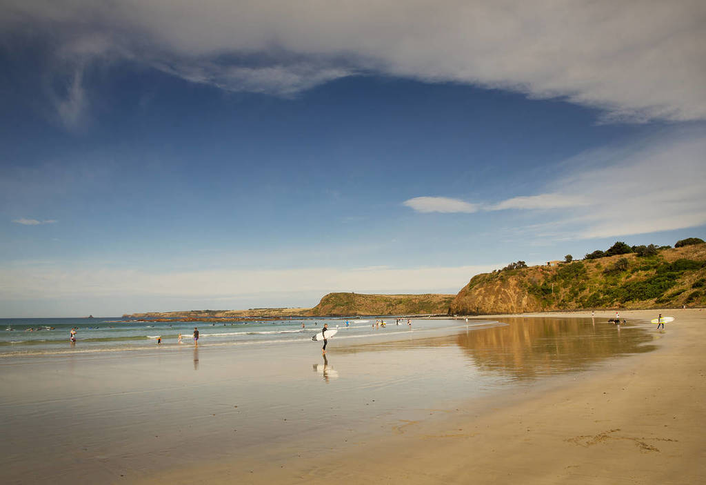 surfer walking on sand at low tide at Smiths Beach