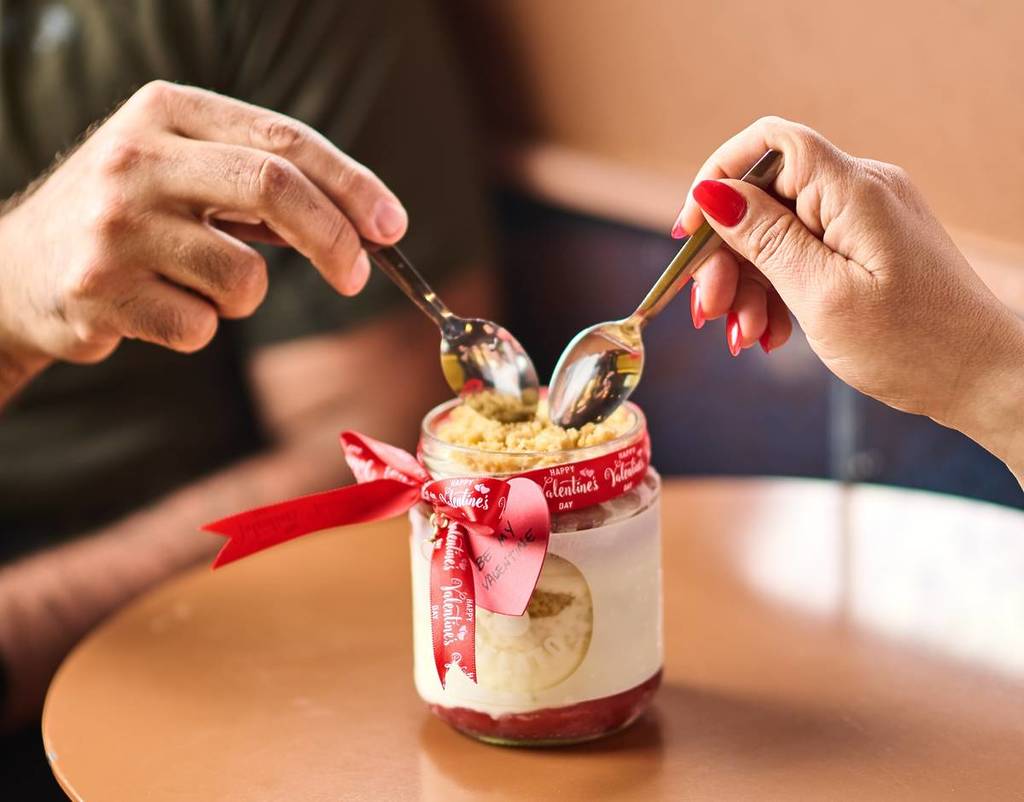 two spoons dipping into a strawberry kisses dessert jar