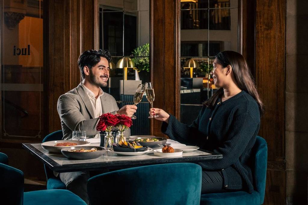 a couple clinking glasses at their table in Luci