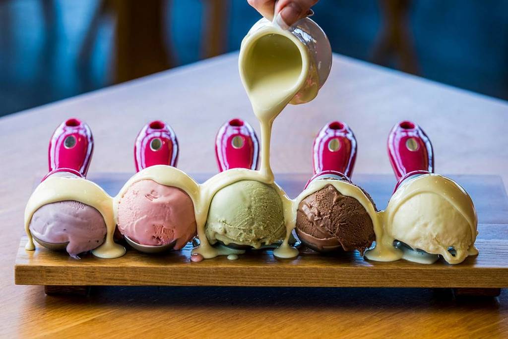 Sauce being poured over ice cream scoops