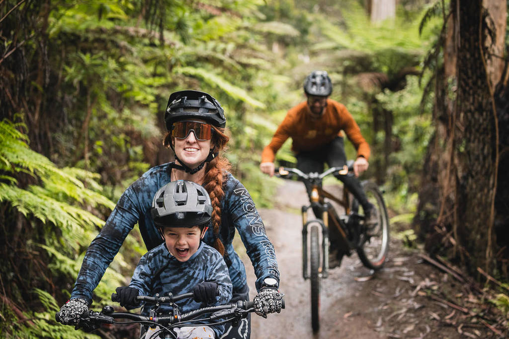 mum and child sharing a bike, while man rides behind, at Warburton Bike Park