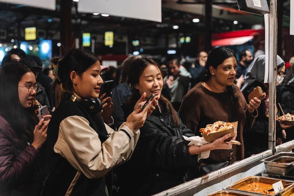 people at Queen Victoria Market taking a photo of their food