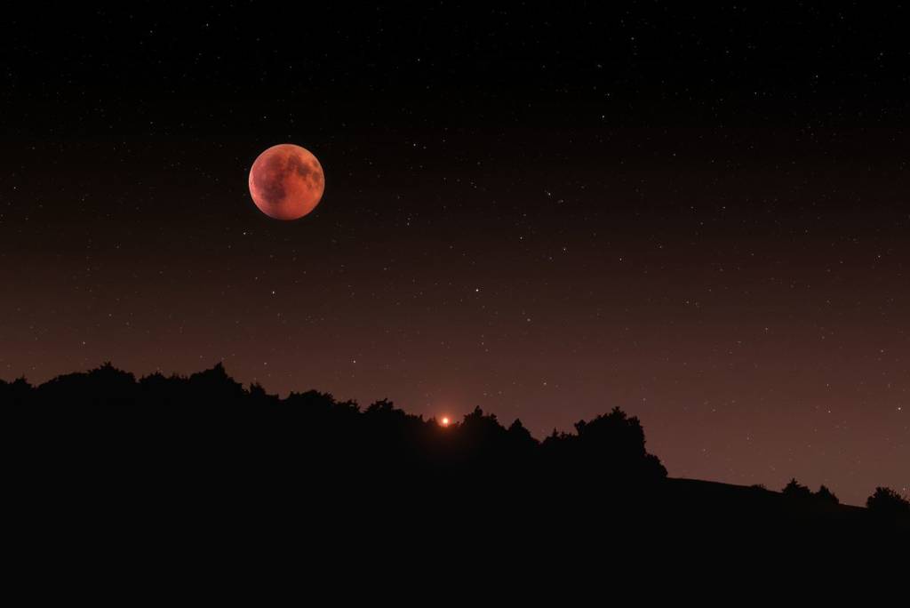 Blood moon rising above mountains in Total Lunar Eclipse