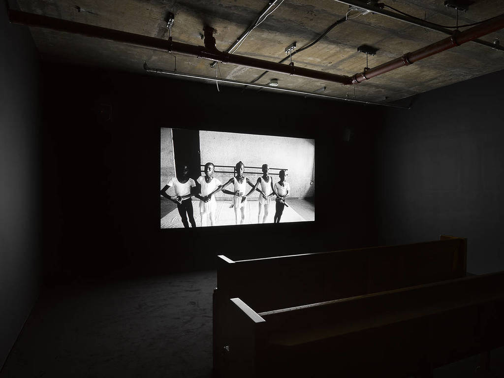 screen in a room showing a black and white image of young ballet students
