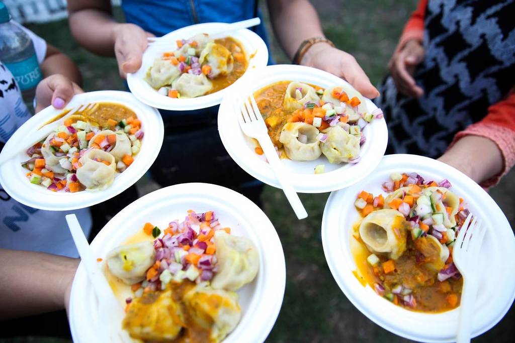 people holding takeaway plates of momo at the food festival