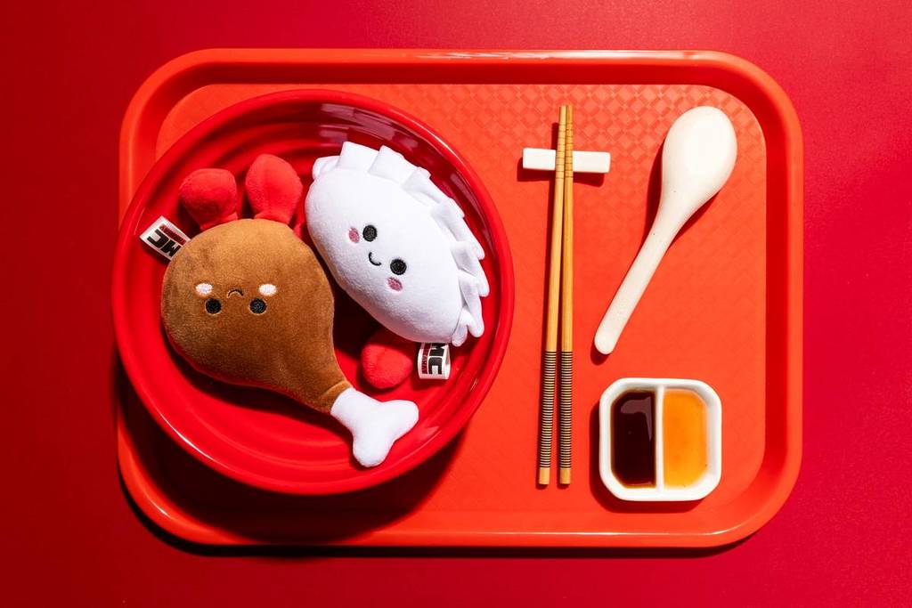 a chicken and dumpling plushie on a takeaway tray with cutlery and sauce