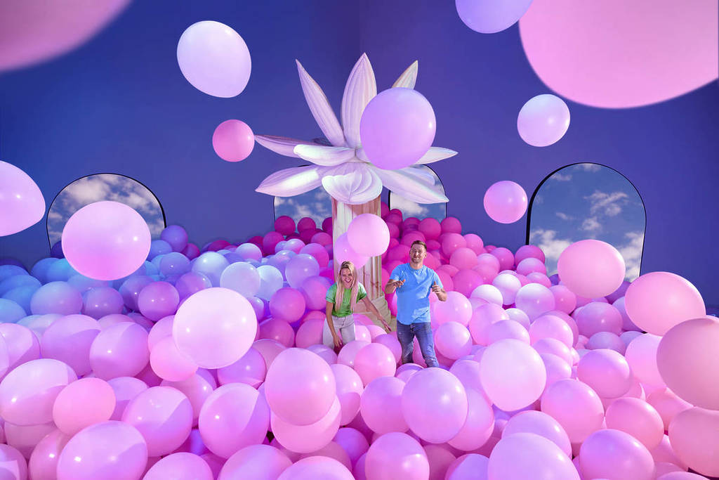 A man and a woman play in a giant balloon pit at Bubble Planet.