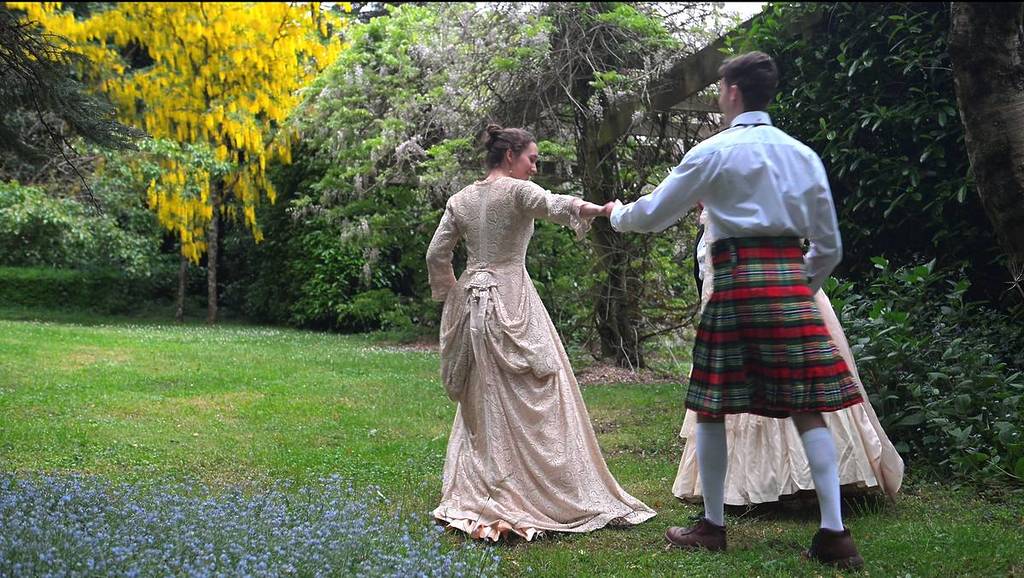 a couple dressed up in Victorian costume walking through the gardens of Duneira Estate