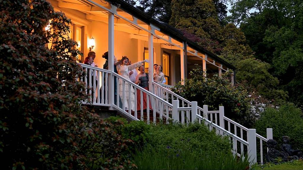 people laughing outside the house at Duneira Estate at dusk, during the Victorian Ball