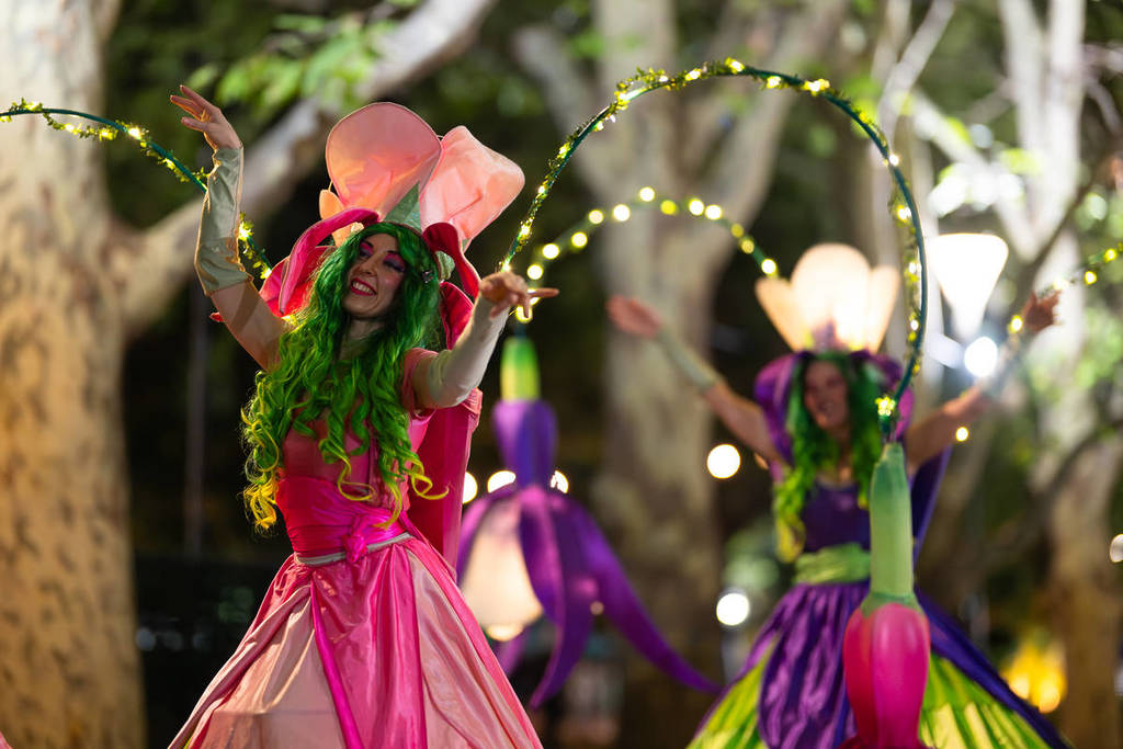 colourfully dressed entertainer holding LED lights in the Gardens by Twilight event