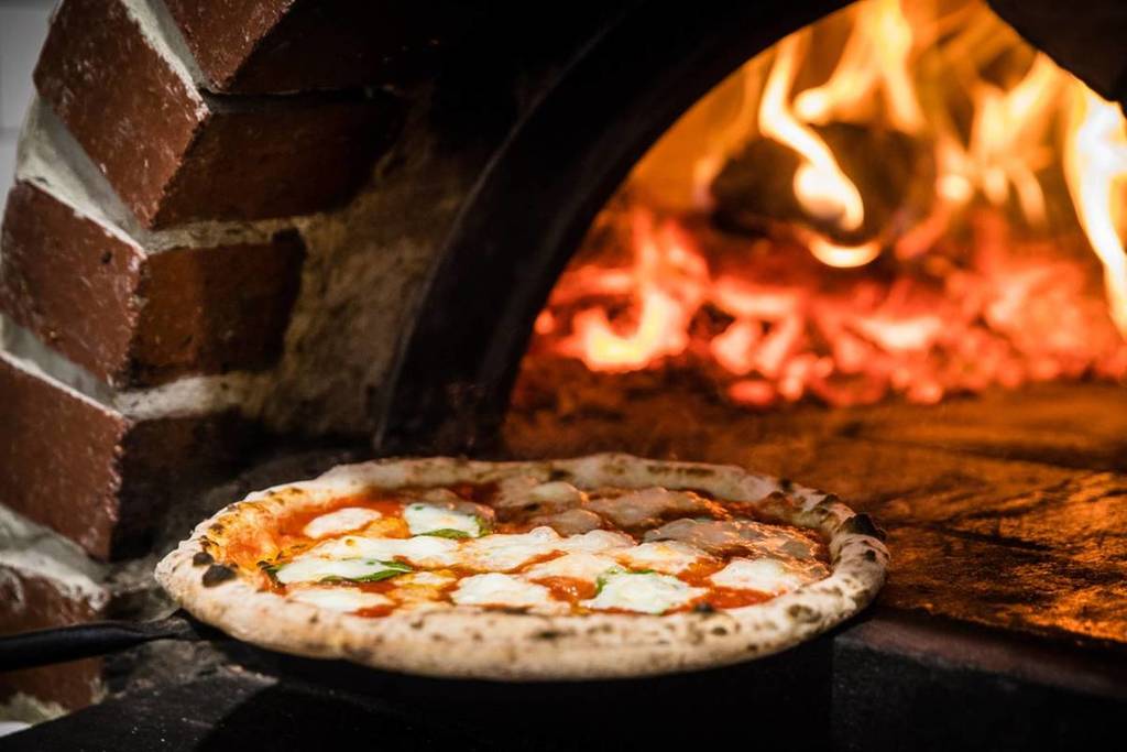 cheesy pizza from Shop225 coming out of a woodfired oven