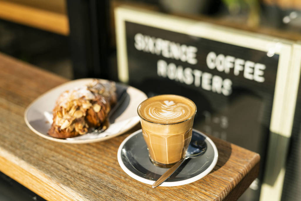 Coffee and pastry on an outdoor cafe table in Bright with a roastery sign in the background