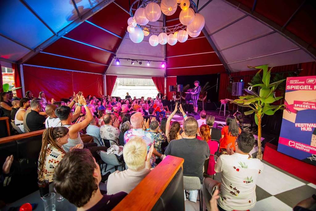 people under a tent in Spiegel Haus watching a live performer