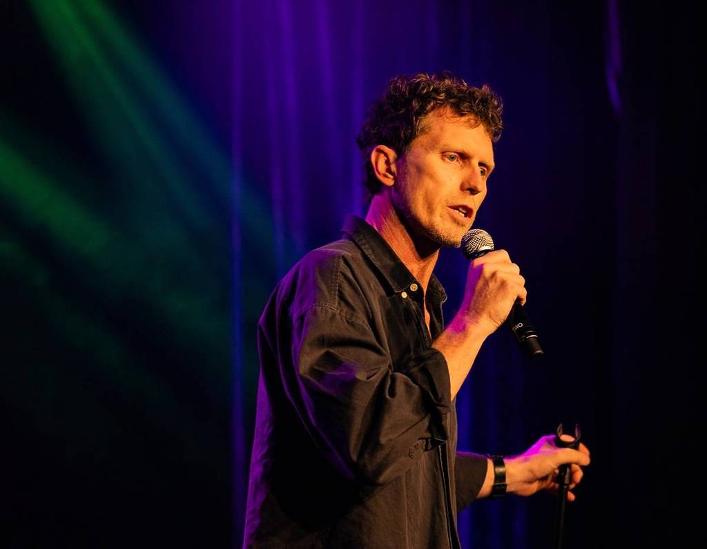 David Quirk holding a mic during a stand-up comedy set