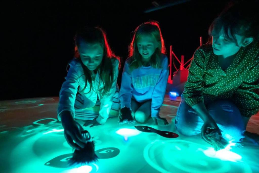 children playing with a light projection on a table