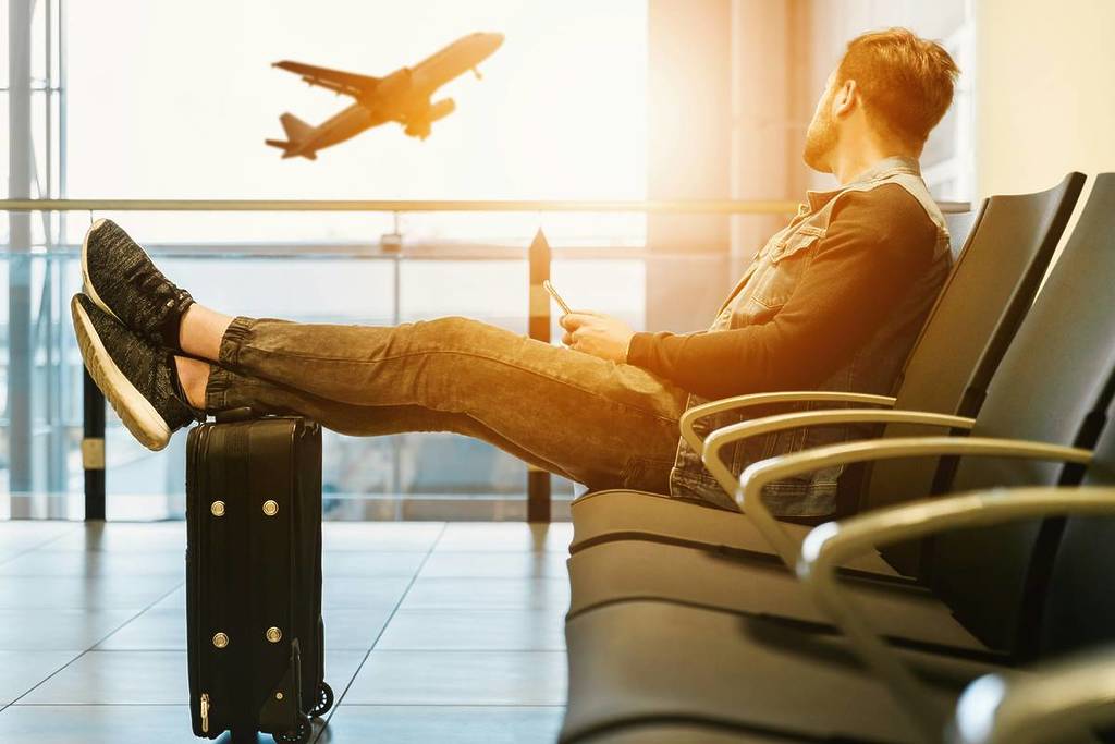 man in an airport lounge watching a plane leave
