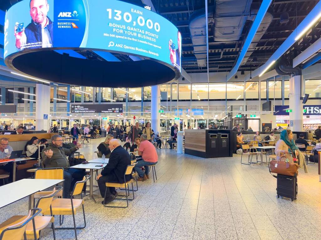 passengers sitting in a terminal that looks a bit like a food court, waiting to board their planes at Melbourne Airport
