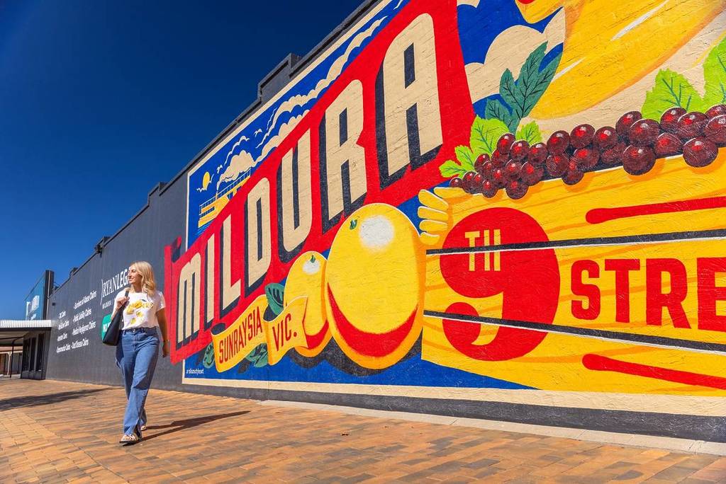 woman in front of a street at mildura that says Mildura and depicts fruit