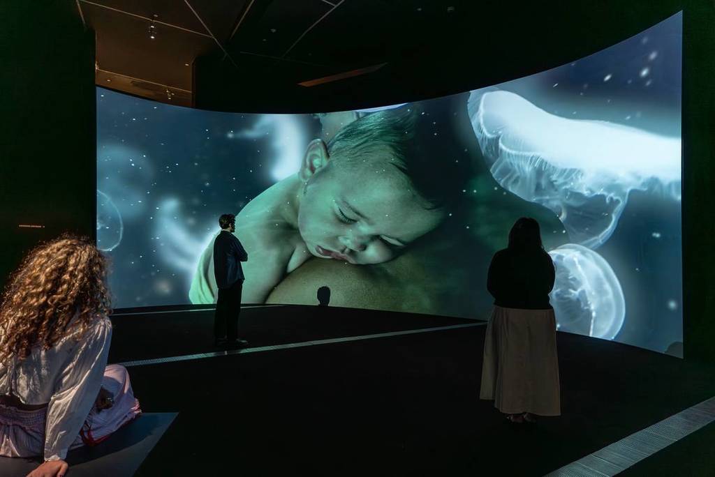 person looking at a projection of a baby at the NGV MOTHER exhibition