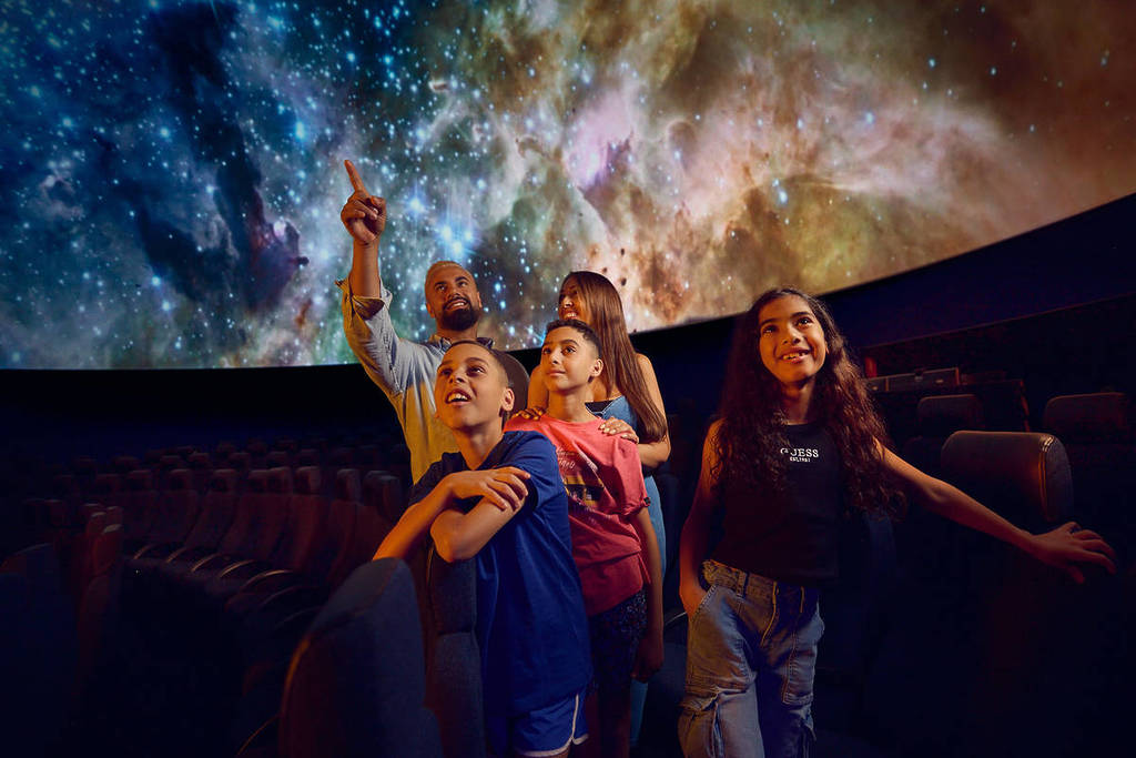 a family with three kids looking up at a galaxy in Melbourne Planetarium