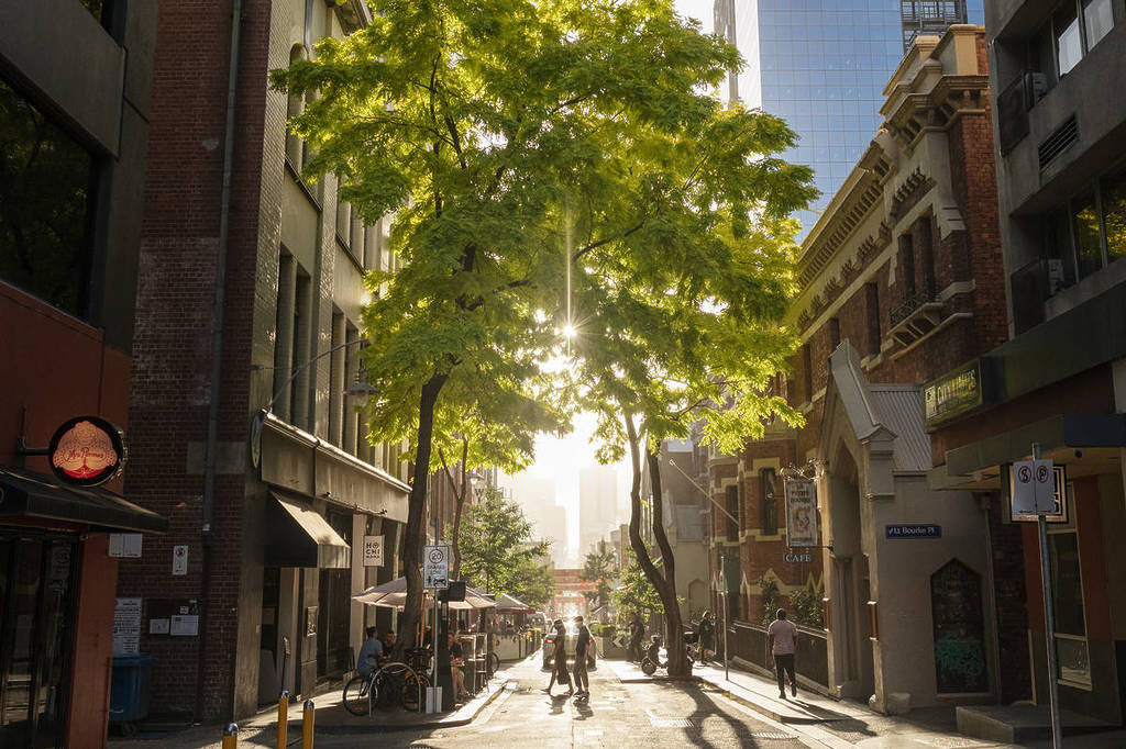people walking across Little Bourke Street during golden hour