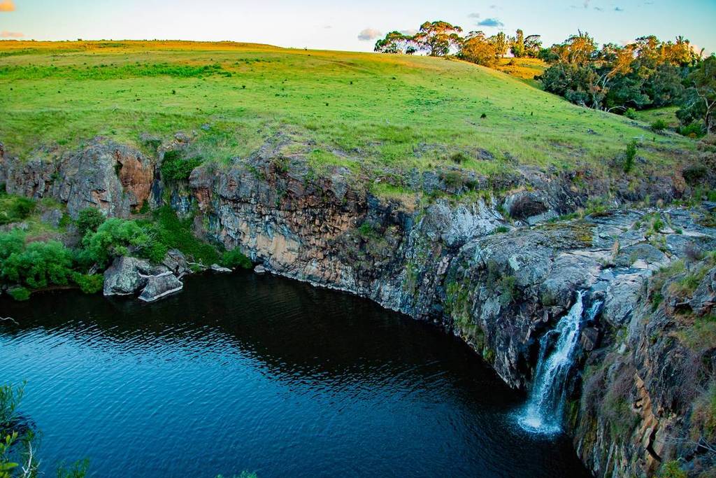 aerial view from the side showing Turpins Falls and a grassy field high above the pool