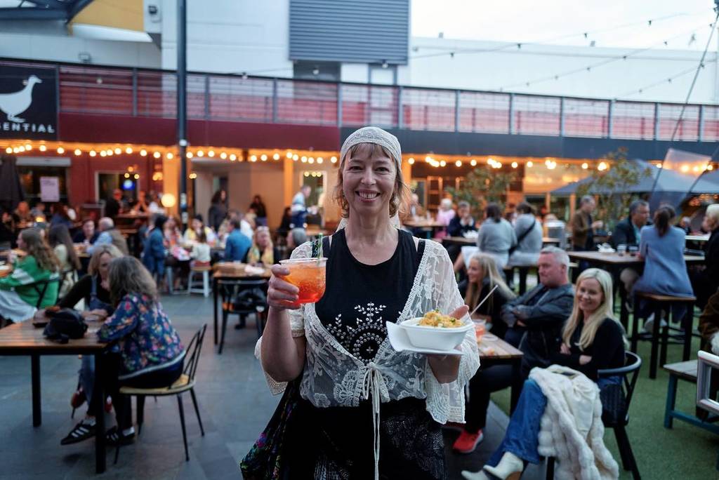woman holding mac and cheese and a drink at Prahran Market
