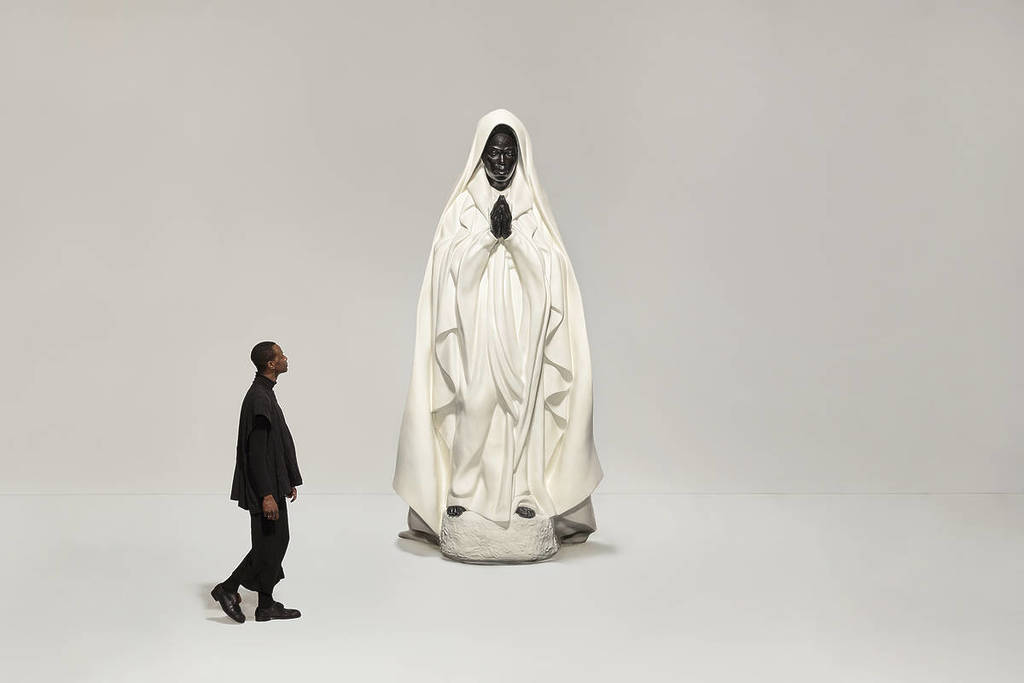 people walking past sculpture by Zanele Muholi resembling the Virgin Mary