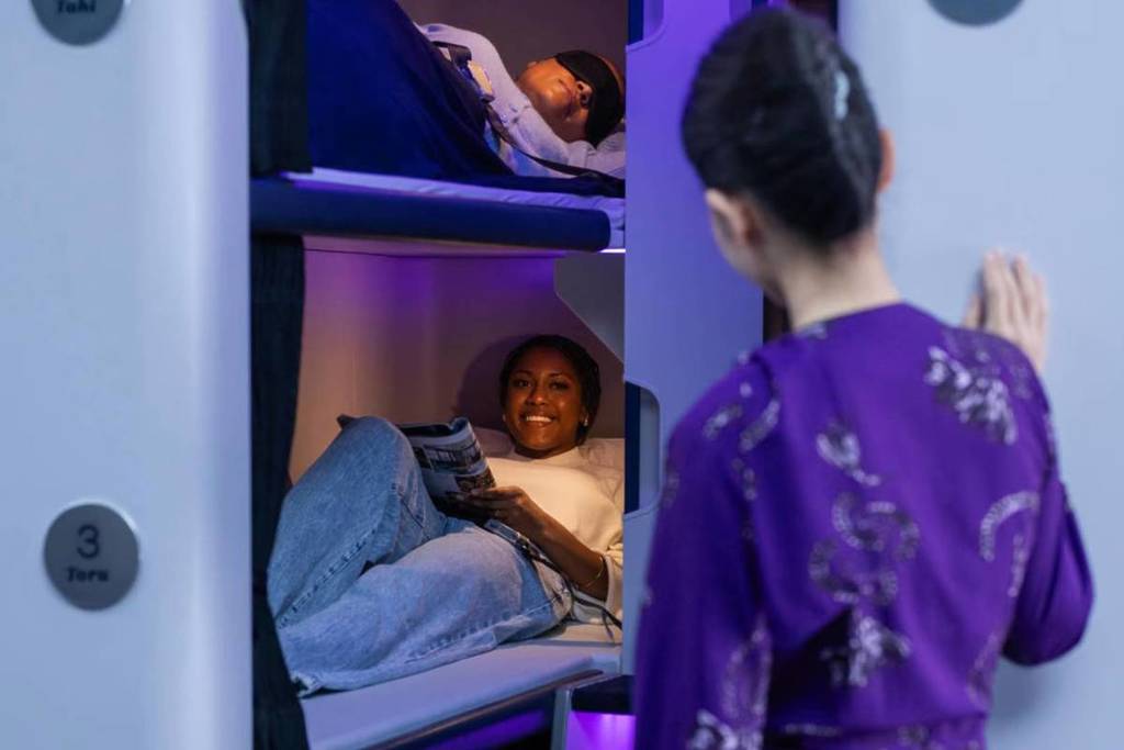 flight attendant checking on passenger who is reading in the Skynest pod